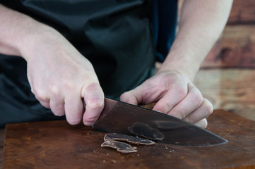 Portion of Beef Jerky cutting into slice on a cutting table with dark beer glass and a kitchen...
