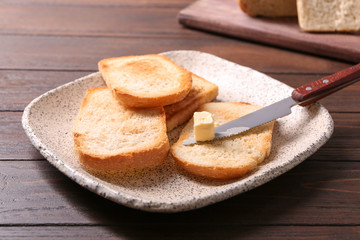 Plate with tasty toasted bread and butter on table