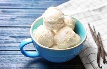 Cup with delicious vanilla ice cream on table