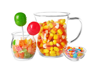 Glassware with different colorful candies on white background
