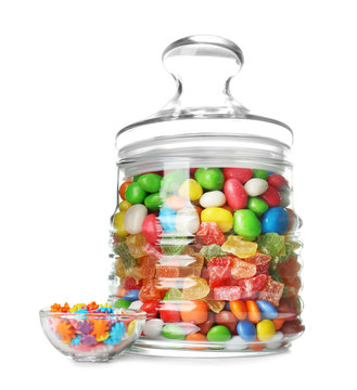 Glass jar with different colorful candies on white background