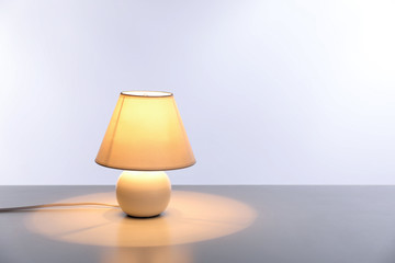 Stylish lamp on table against light background