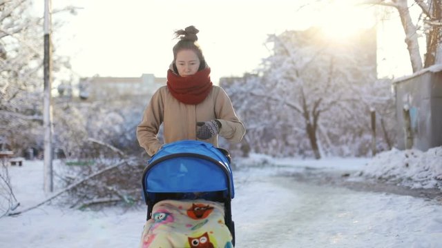 Worried young woman strolling with her little sleeping son in a carriage. beautiful snowy winter landscape maternity leave social welfare parenthood trouble thoughful pensive face walk healthcare