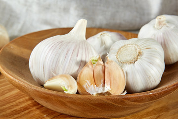Garlic close up on wooden plate on rustic background, shallow depth of field, selective focus, macro