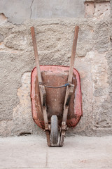 Fototapeta na wymiar Old wheelbarrow against a wall in Trinidad, Cuba.