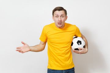 Bewildered young European man, fan or player in yellow uniform hold soccer ball, cheers, worries about losing football team isolated on white background. Sport play football healthy lifestyle concept.