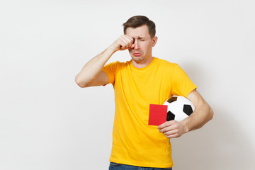 European sad upset crying shocked young man, football fan or player in yellow uniform hold in hand...