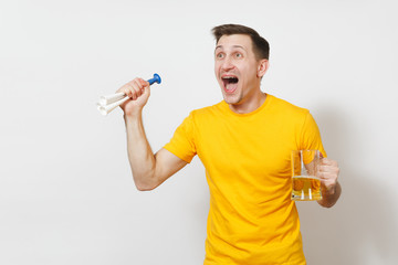 Inspired young fun cheerful European man, fan or player in yellow t-shirt hold pint mug of beer, football pipe cheer favorite team isolated on white background. Sport, student, play lifestyle concept.