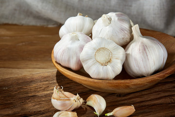 Garlic close up on wooden plate on rustic background, shallow depth of field, selective focus, macro