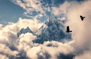 Fotobehang Manaslu Twee vliegende vogels tegen majestueuze Manaslu-berg met besneeuwde piek in wolken in zonnige heldere dag in Nepal. Landschap met mooie hoge rotsen en blauwe bewolkte hemel. Natuur achtergrond. Feeënscène