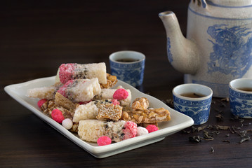 Chinese snack in white dish and Chinese teapot with hot Chinese tea in cup