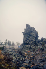 Fog and mountains in the morning with mystic light in the fjords of New Zealand. Green slope and cloudy peak.