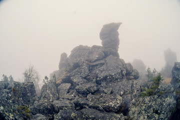 Dark mountain landscape with big mysterious rocks covered by fog
