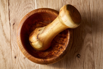 Top view close-up picture of wooden pestle and mortar on brown rustic wooden background, shallow...
