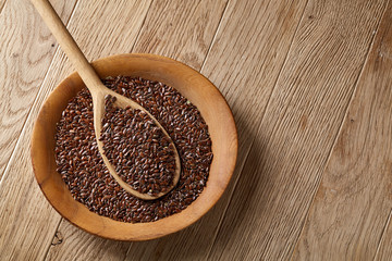 Wooden spoon with flax seeds in a plate on rustic background, top view, close-up, shallow depth of field