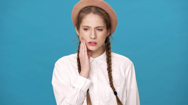 Portrait of caucasian woman suffering from toothache and touching cheek needing dental amalgam, isolated over blue background