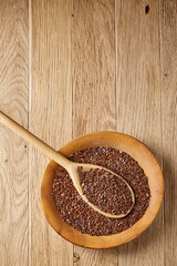 Wooden spoon with flax seeds in a plate on rustic background, top view, close-up, shallow depth of field
