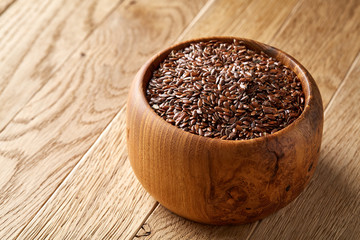 Flax seeds in wooden bowl on rustic wooden background, top view, shallow depth of field