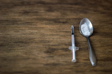 spoon with a dose of drugs and a syringe on the table