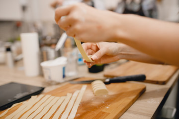 Fototapeta na wymiar Girl cuts the dough for making Italian pasta