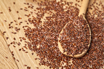 Flax seeds in wooden bowl and spoon on rustic wooden background, top view, shallow depth of field
