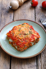 lasagna tradizionale italiana con salsa bolognese e parmigiano su sfondo rustico