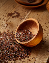An overturned wooden bowl with linseeds on a rustic background, close-up, shallow depth of field, selective focus