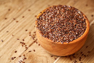 An overturned wooden bowl with linseeds on a rustic background, close-up, shallow depth of field, selective focus
