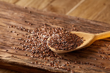 Wooden spoon with flax seeds on rustic background, top view, close-up, shallow depth of field, selective focus