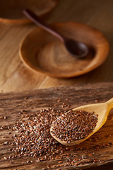 Wooden spoon with flax seeds on rustic background, top view, close-up, shallow depth of field, selective focus