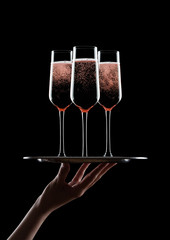 Hand holds tray with pink rose champagne glasses