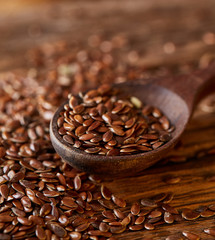 Wooden spoon with flax seeds on rustic background, top view, close-up, shallow depth of field, selective focus