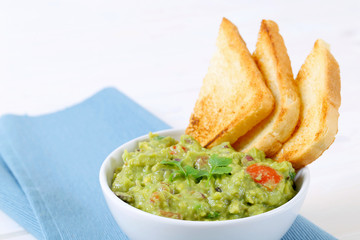 bowl of guacamole with toast