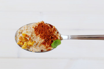 spoon of oatmeal porridge with cinnamon and walnuts