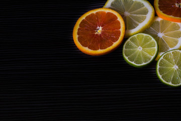 Fototapeta na wymiar lemon, orange and lime on a black background