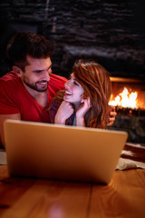 Smiling couple watching movie on laptop at home. Technology, internet and people concept