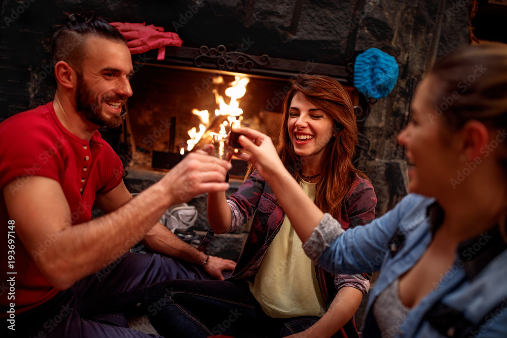 Wall mural Smiling friends cheering with drinks after skiing day