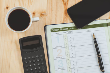 personal project planner with fountain pen and hot coffee on wood table.