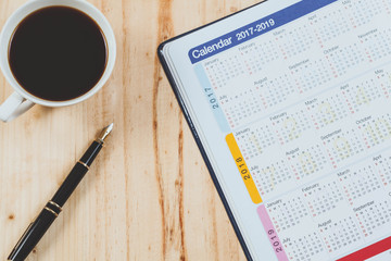 Calendar planner with fountain pen and hot coffee on wood table.office tool.