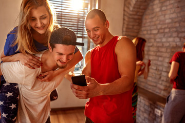 Smiling dancers rest during a break and communicate with each other and use mobile phone