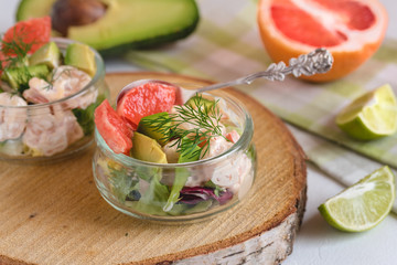 Cocktail salad with shrimp, avocado, green lettuce, grapefruit and mayonnaise sauce in a glass.