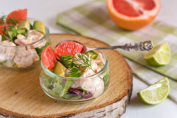 Cocktail salad with shrimp, avocado, green lettuce, grapefruit and mayonnaise sauce in a glass.
