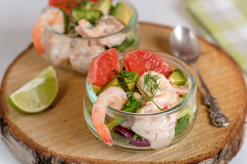 Cocktail salad with shrimp, avocado, green lettuce, grapefruit and mayonnaise sauce in a glass.
