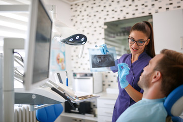 Female dentist showing dental x-ray footage to patient