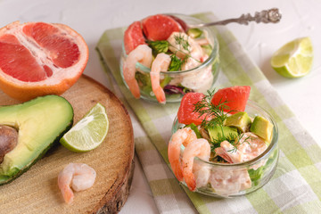 Cocktail salad with shrimp, avocado, green lettuce, grapefruit and mayonnaise sauce in a glass.
