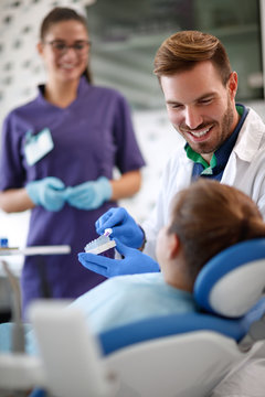 Dentist shows properly brushing teeth model of teeth in jaw