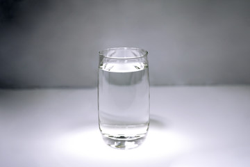 A glass with clear water on gray background.