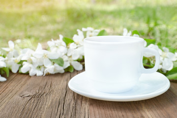 Fototapeta na wymiar White mug and apple flowers on a wooden background. Side view
