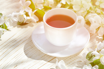 Obraz na płótnie Canvas Mug of tea and apple blossom on a wooden background.