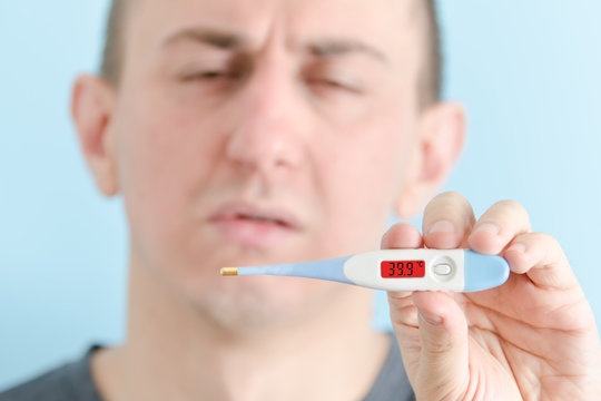 Man With A Thermometer In His Hand. Increased Body Temperature